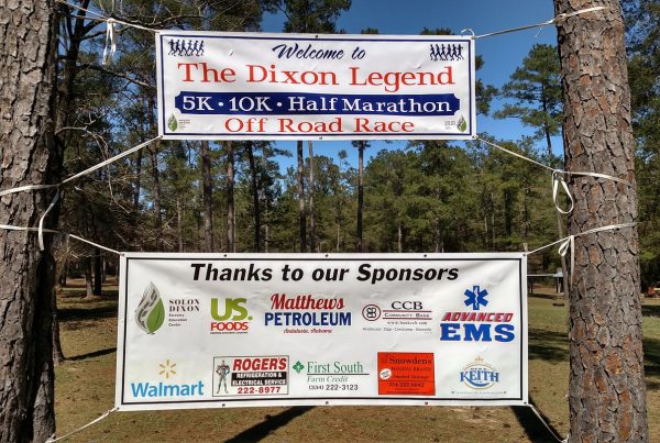 Two Dixon Legend Race signs hang from trees