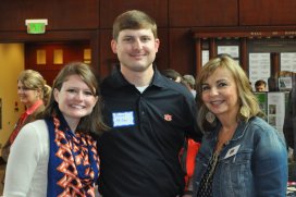 two young alumni and staff at event