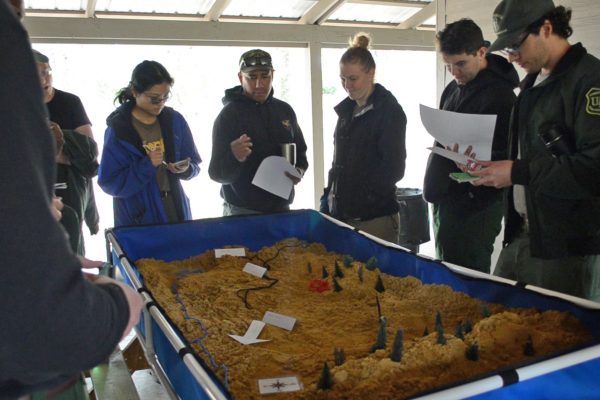 Wildland Firefighter Apprenticeship Program instructors use a sand table to teach and evaluate tactical decision-making skills.
