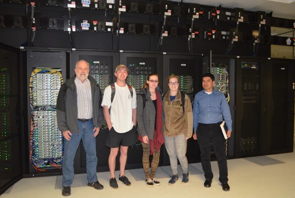 SFWS Professor Sanjiv Kumar and students stand in front of "Hopper" supercomputer.