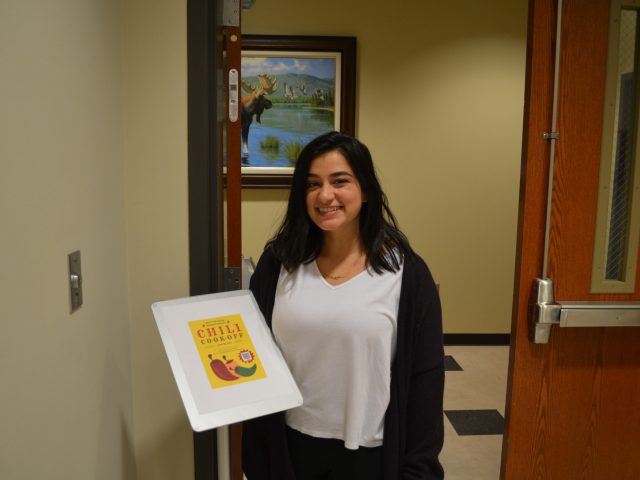 Society of Natural Resources president Marisa Juarez stands with the event poster before the cook-off.