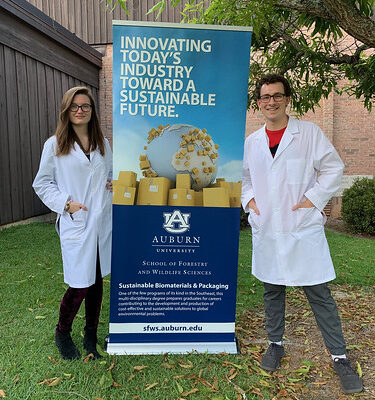 Students Autumn Reynolds and Philip McMichael with a Sustainable Biomaterials and Packaging banner.