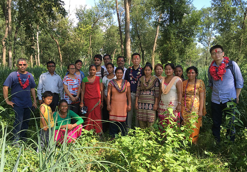 Zhang, shown center in the blue shirt, is pictured visiting with community members near a village in Nepal, where he toured a community forest restoration project.