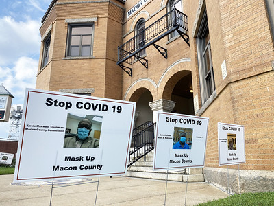 "Stop COVID-19, Mask Up Macon County" yard signs pictures in front of a building.
