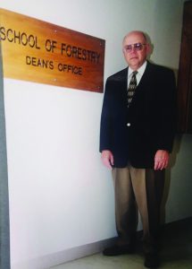 Dean Emmett Thompson stands in front of School of Forestry sign
