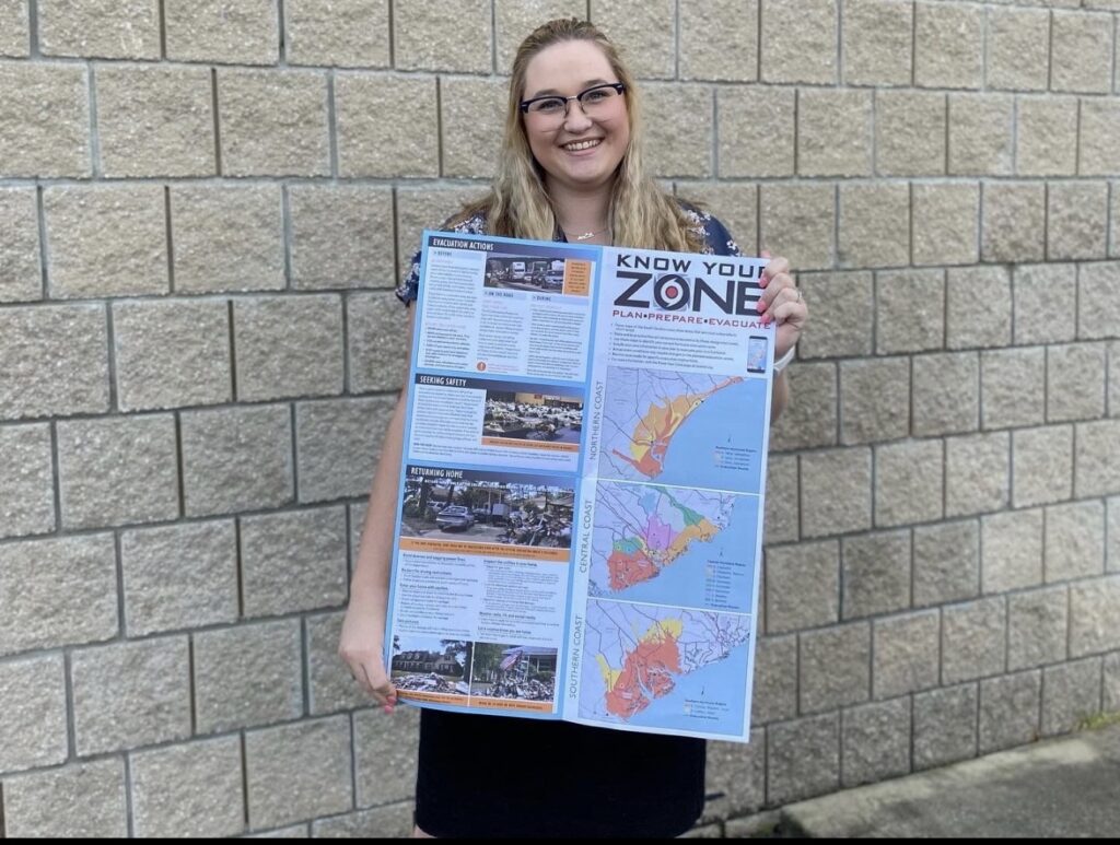 Emily proudly holds her Know Your Zone map, a map that is part of the 2022 South Carolina Hurricane Guide, marking the first public release of her impactful maps.