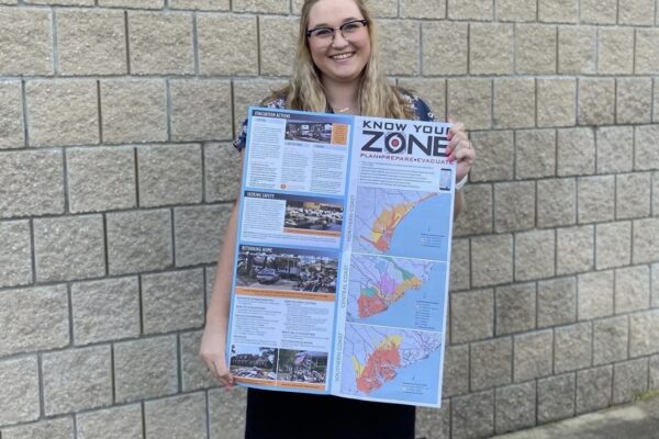 Emily proudly holds her Know Your Zone map, a map that is part of the 2022 South Carolina Hurricane Guide, marking the first public release of her impactful maps.
