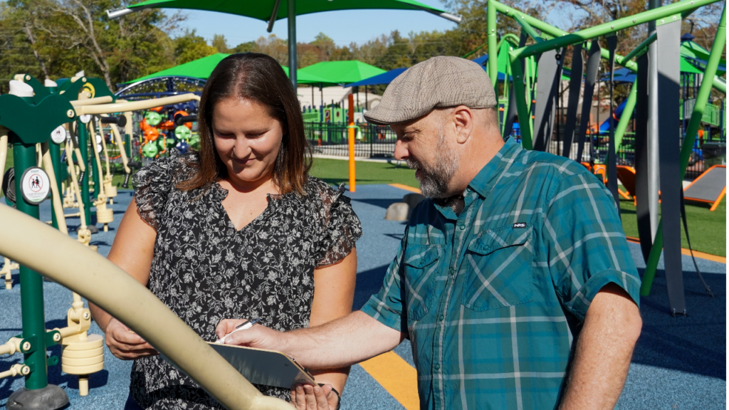 Allie McCreary and Wayde Morse examine a piece of accessible play equipment 