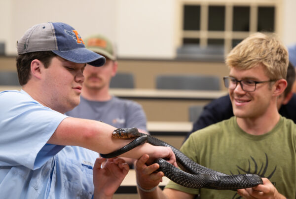 Two Auburn students holding an Indigo Snake.