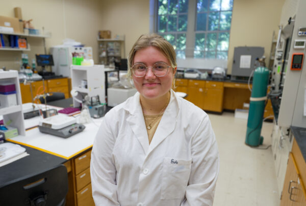 Woman in white lab coat smiling in lab.