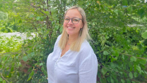 Allie Foster poses for a headshot in a forested backdrop.