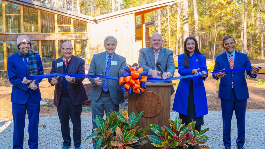 Auburn University leadership stand at the event podium for the ribbon cutting.