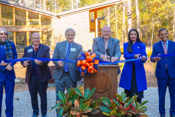 Auburn University leadership stand at the event podium for the ribbon cutting.