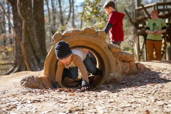 A preschooler crawls through a tunnel on a playground