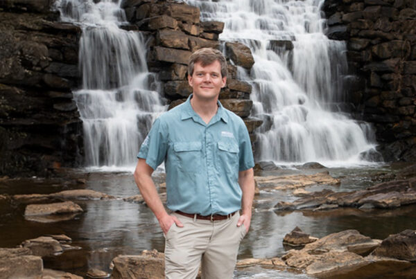 Matthew Capps standing in front of a water at Chewacla State Park.