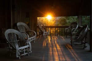 Wooden porch with rocking chairs at sunset.
