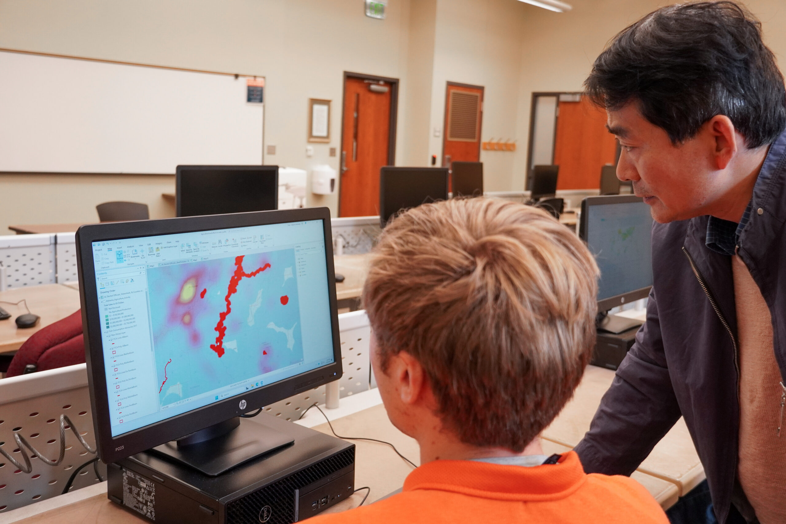 professor instructs student using computer software
