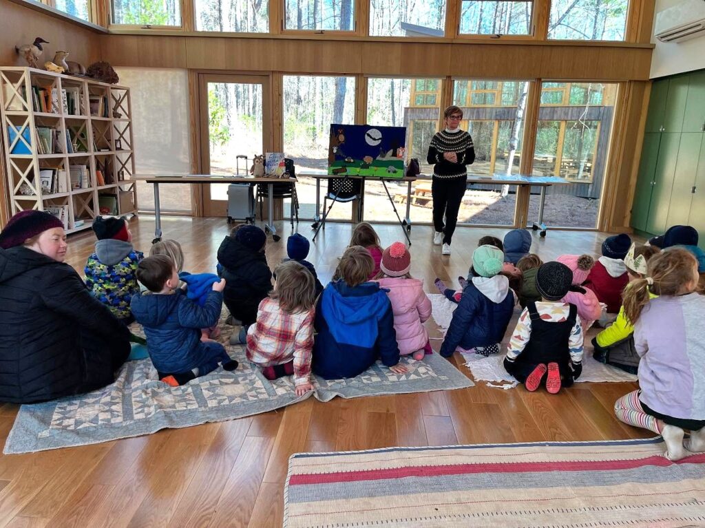 children seated on floor listening to a teacher