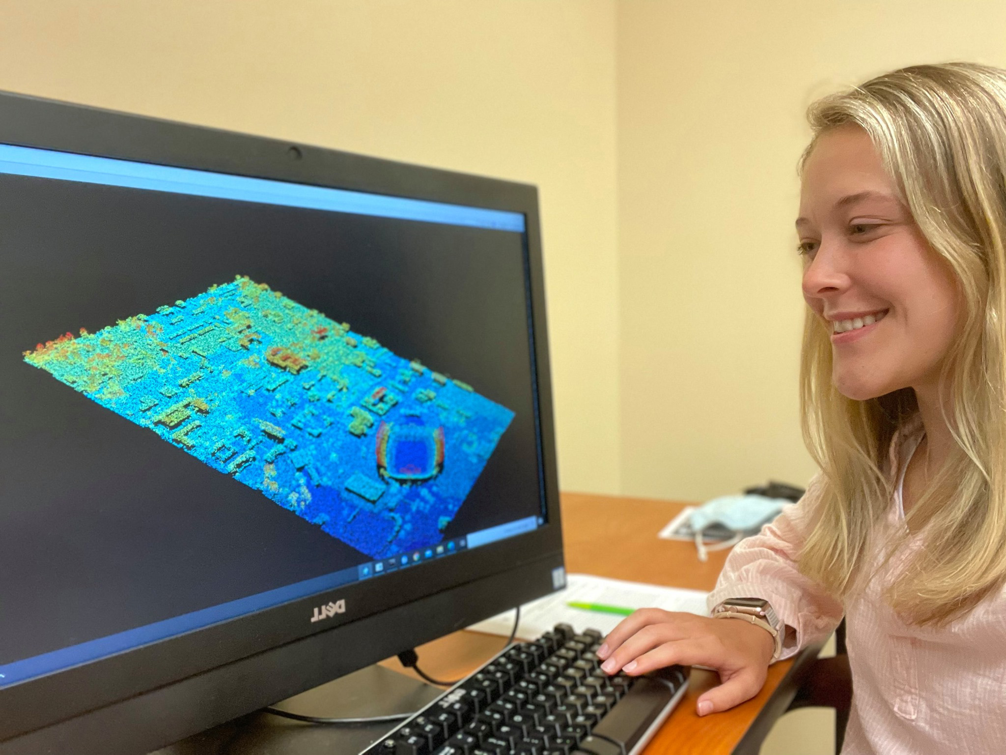 woman smiling as she looks at computer generated image on screen