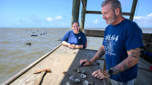 Sower stands next to an oyster farmer on an oyster platform at the Gulf coast.
