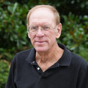 Thomas Elder posed for a headshot in front of a green backdrop.