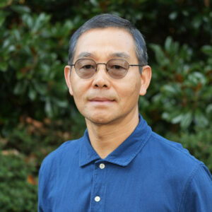 George Cheng stands on front of a green background for a headshot photo.