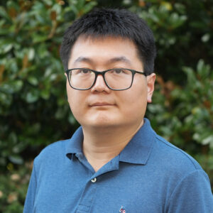 Kunxin Zhu poses for a headshot photo against a green background.