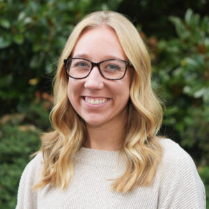Emily Legg poses for a headshot photo in front of a green backdrop.