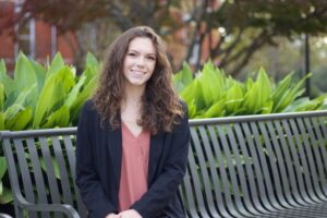Grace Goldsby sitting on a bench smiling 