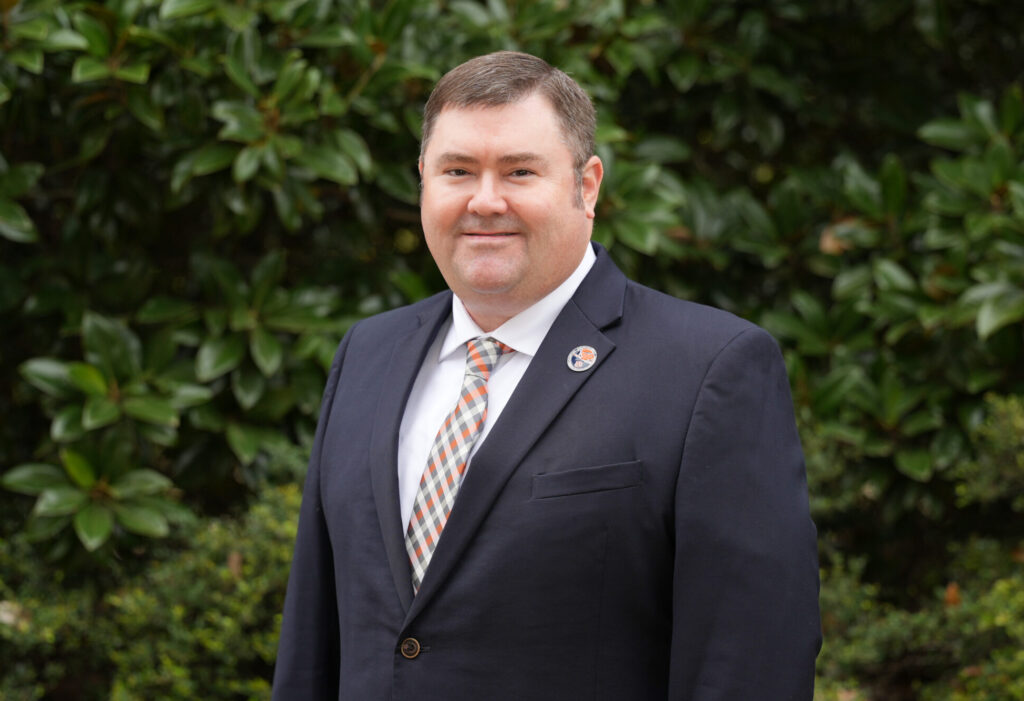 Adam Maggard poses for a photo in front of a green background.