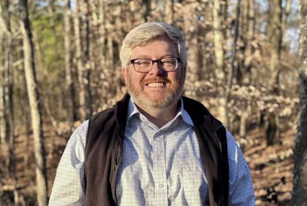Auburn alumnus Daniel Crawford poses for a photo with a forested background.
