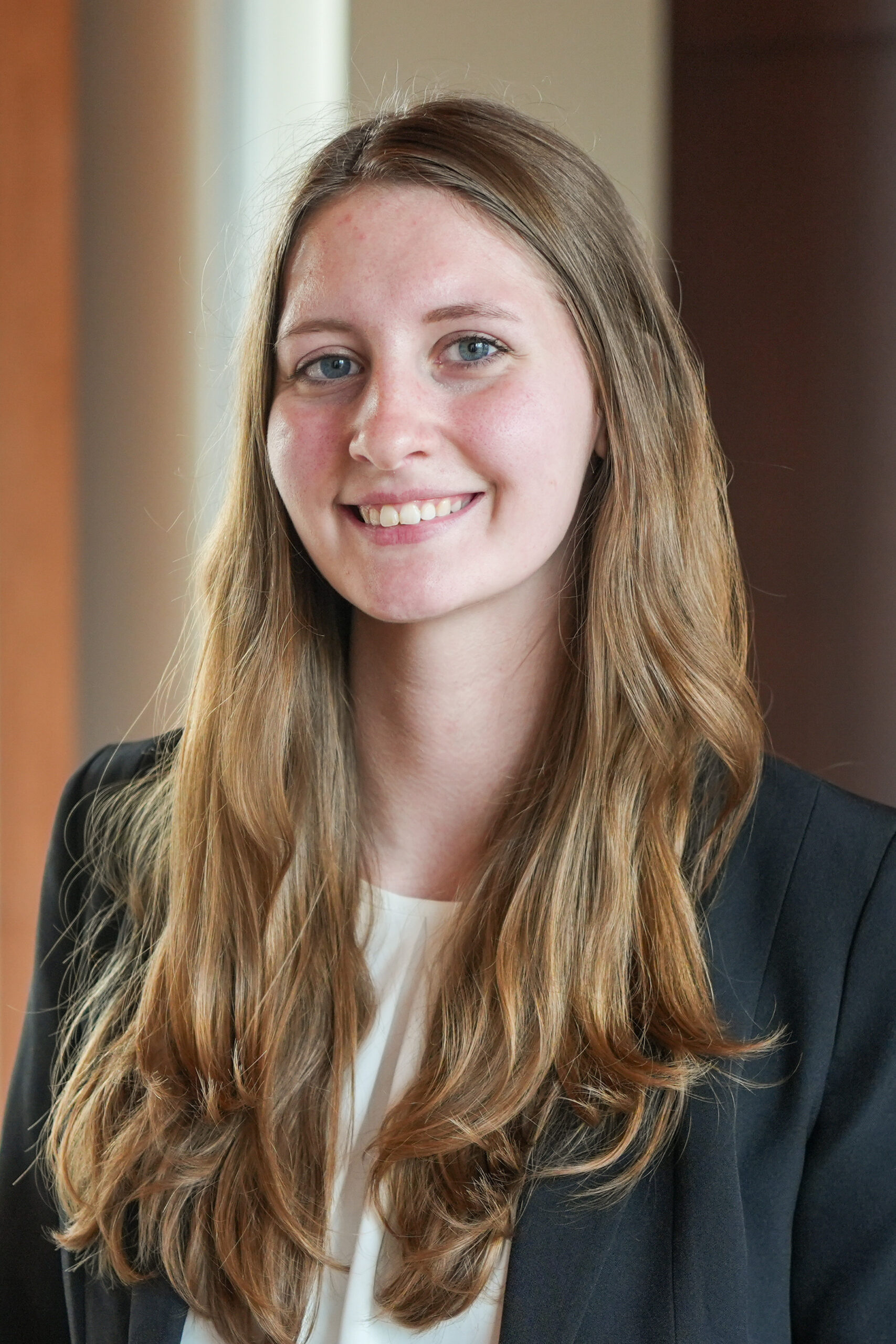 Abby Tipton standing in a dark suit jacket smiling.