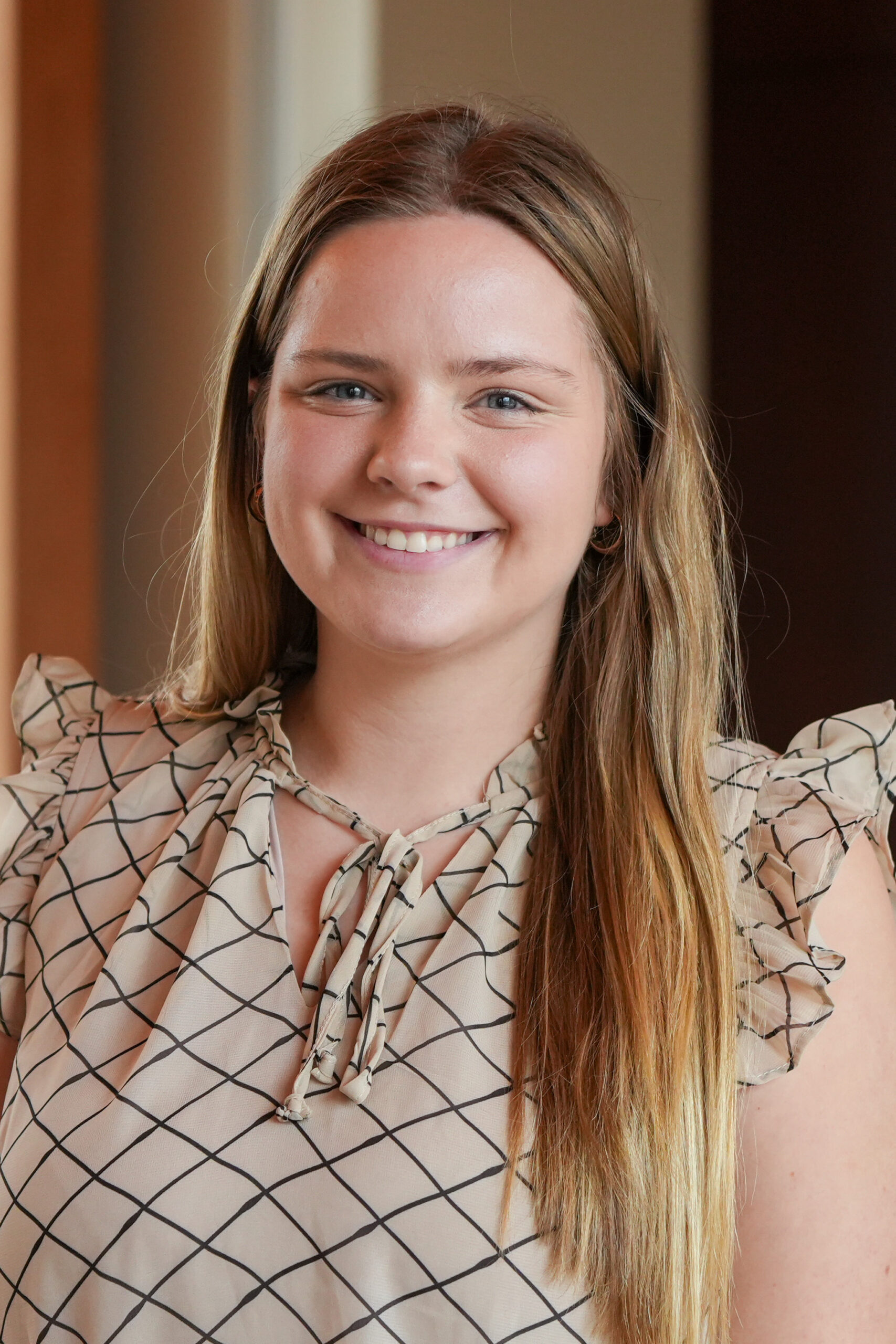 Bella Suiter standing in a tan blouse smiling.