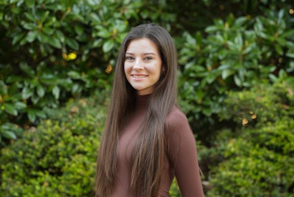 Elizabeth Fritsch standing in front of a tree smiling.