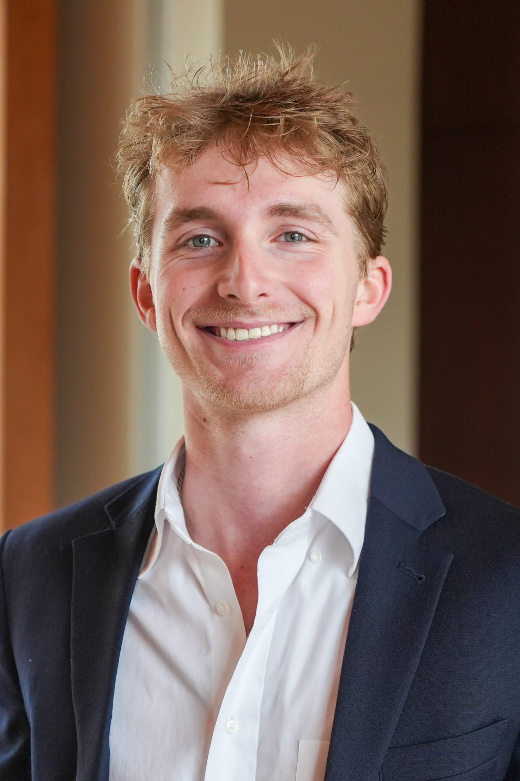 Hardy McMillan standing in a dark suit jacket smiling.
