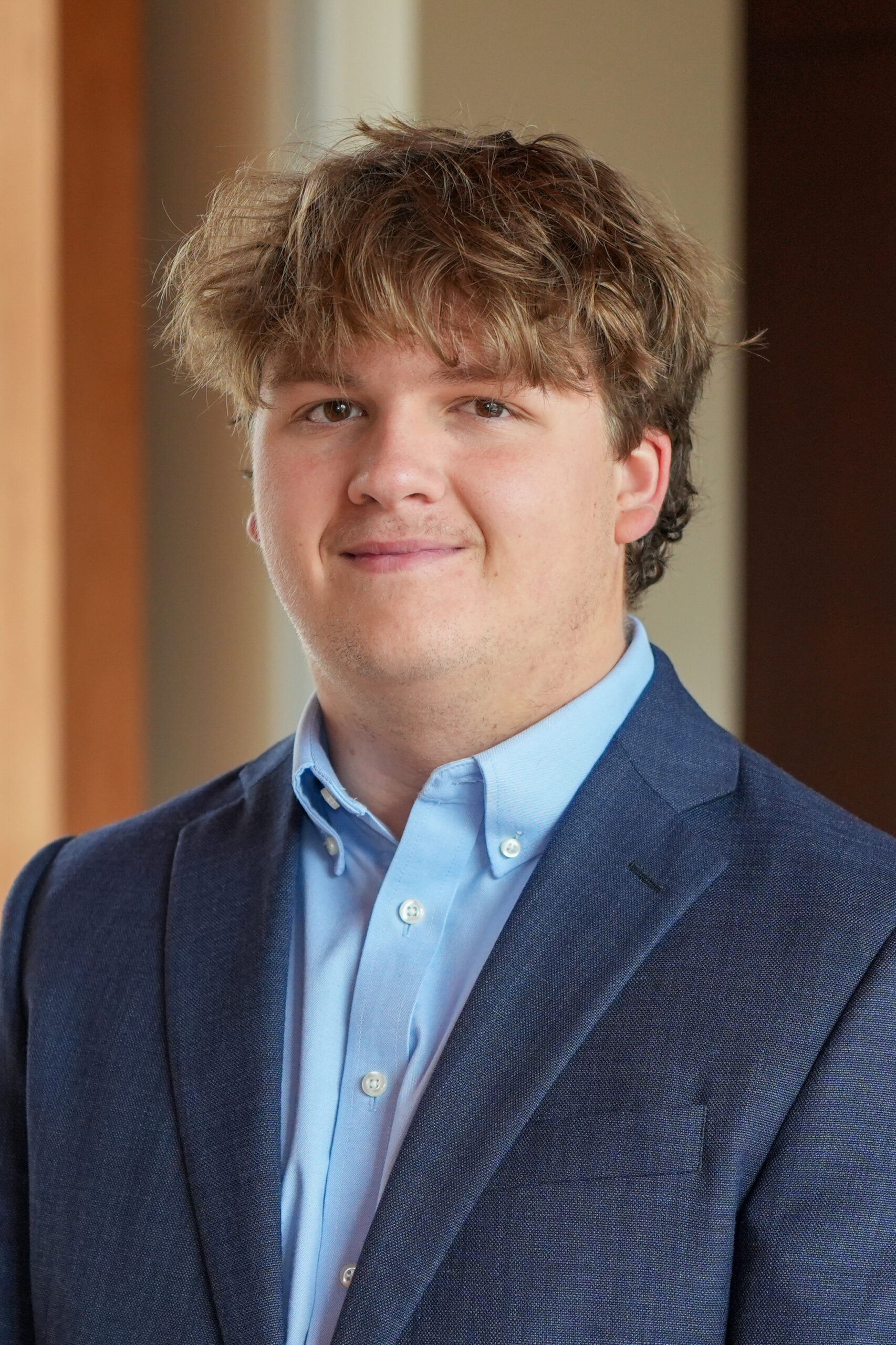 James Butler standing in a blue suit jacket smiling.