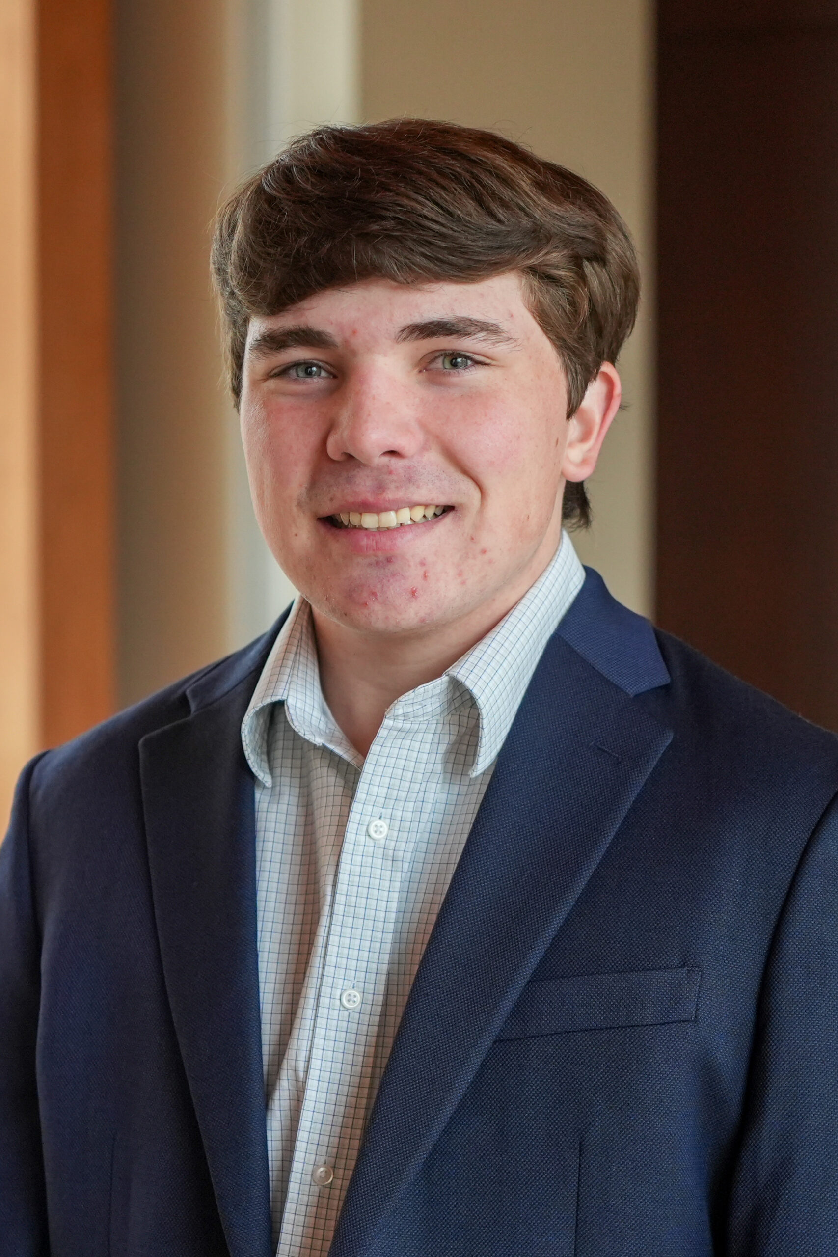 Jonah Sanders standing in a dark blue suit jacket smiling.
