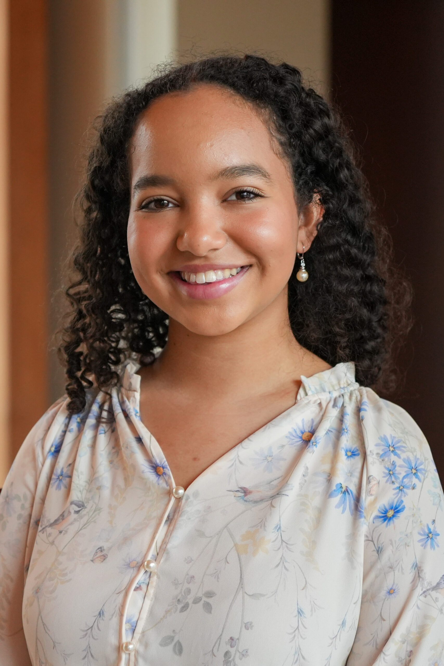 Vienne O'Connor standing in a light blouse smiling.