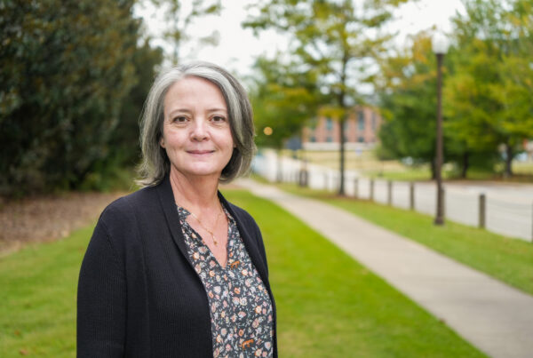 Heather Alexander standing in the grass smiling.