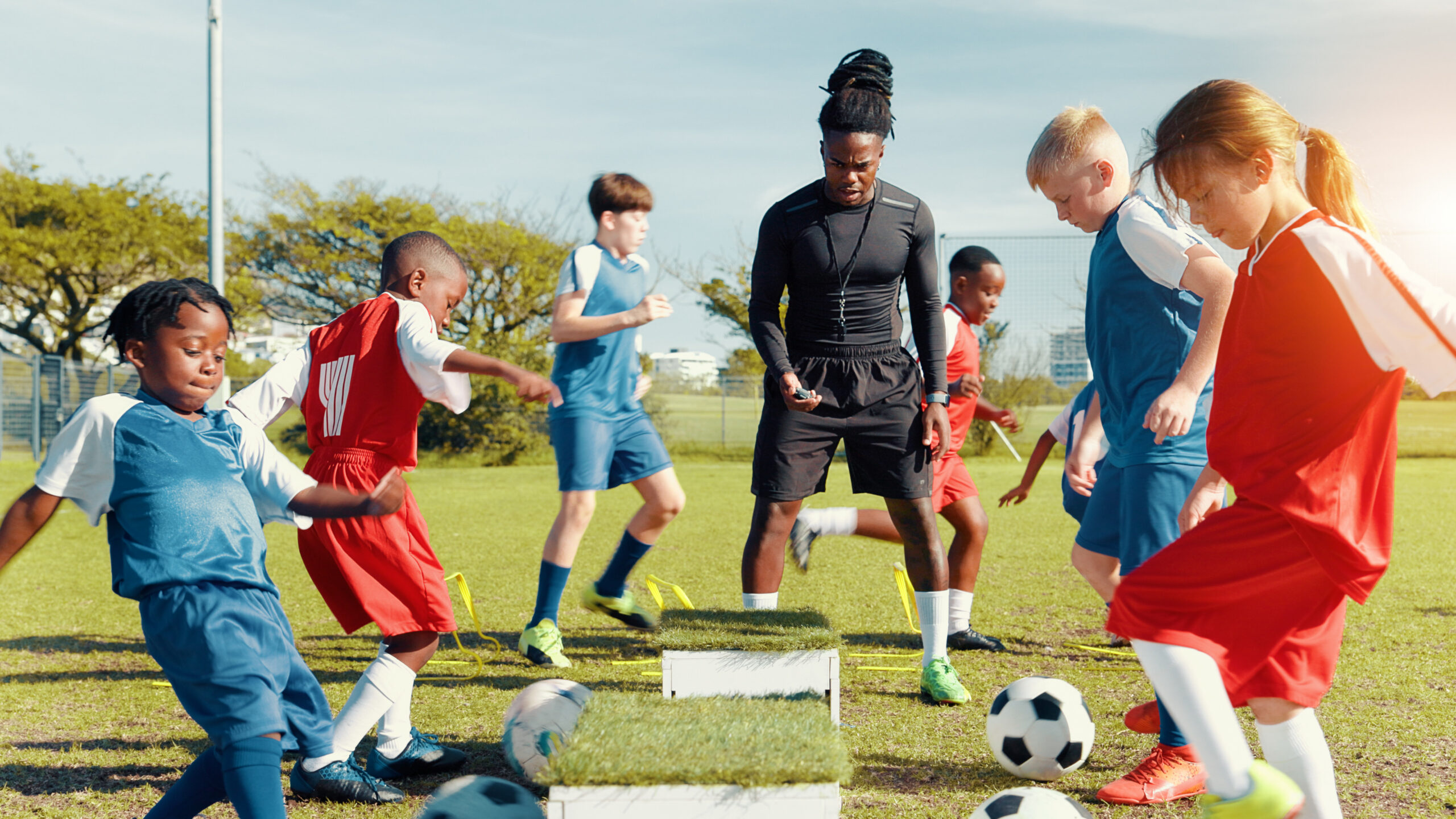 athletic coordinator coaching youth soccer players on a sports field