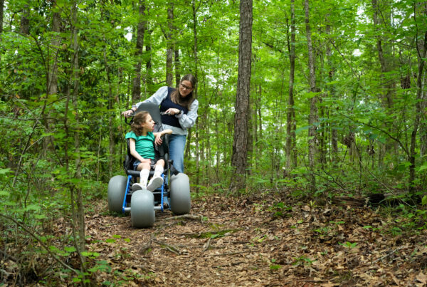 A mother and her physically-impaired daughter enjoy a morning trail ride in a specially designed trail wheel chair.