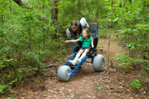 A mother and her physically-impaired daughter enjoy a morning trail ride in a specially designed trail wheel chair.