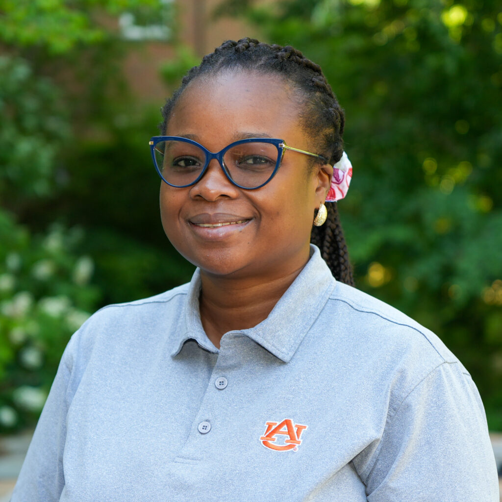 Temitope Foluronso poses for a headshot against a forested background