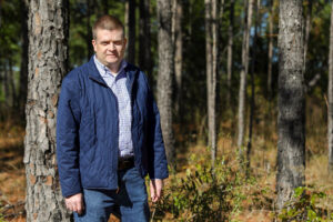 James Parker poses for a photo in a forest.
