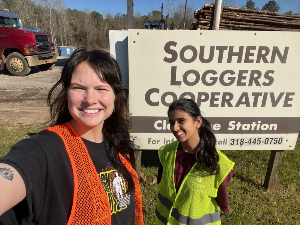 two women stand before a sign that states southern loggers cooperative