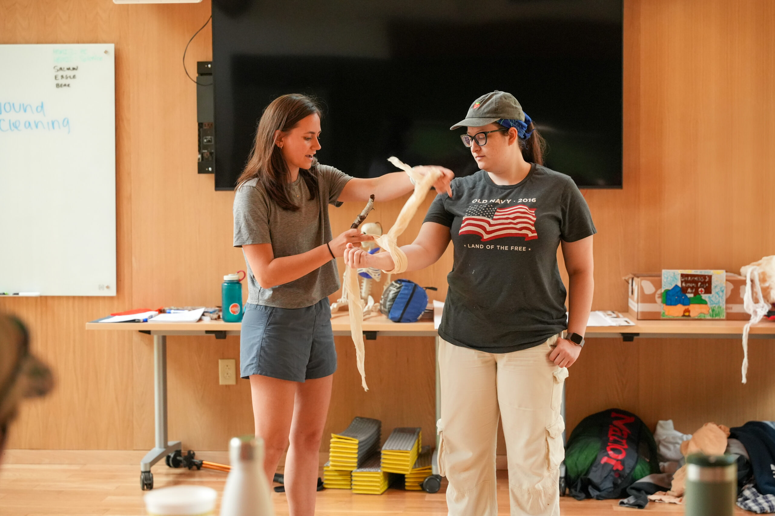 a female recreation leader provides first aid training using the arm of a female student