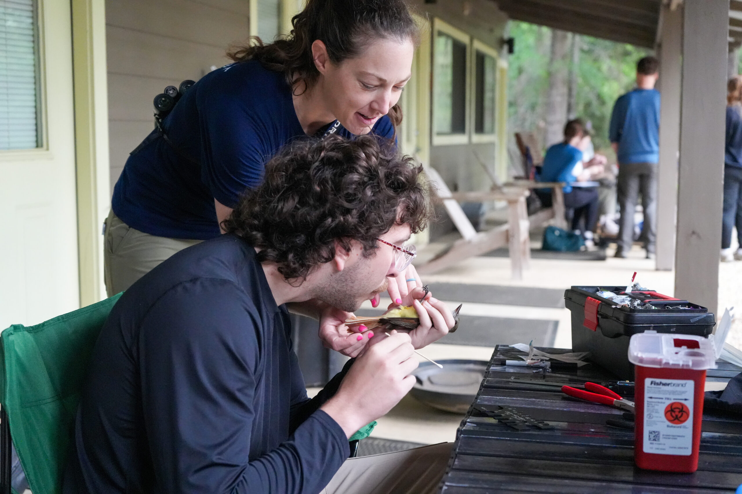 female professor teaches male student to band a bird