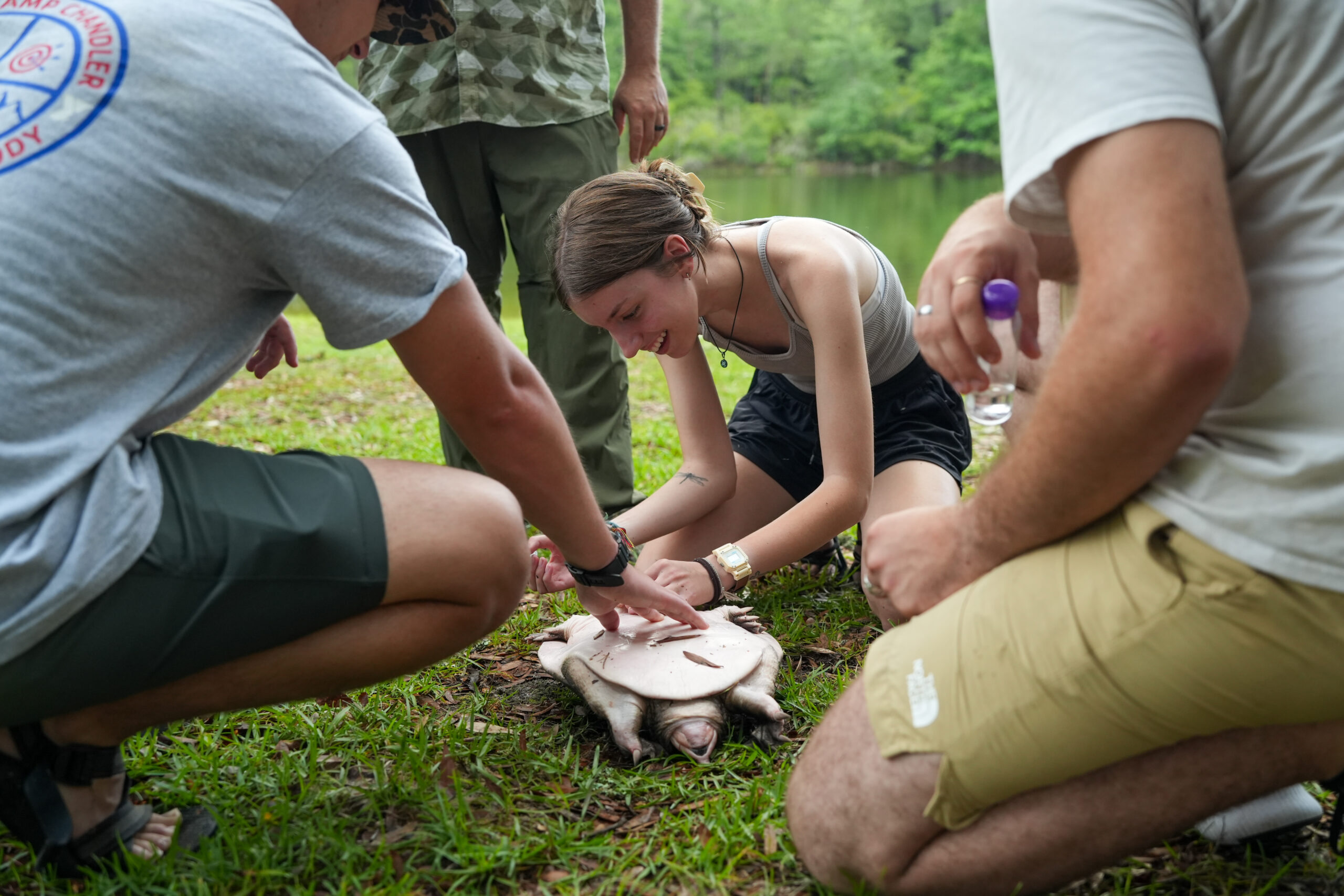 female student measures a turtle next to a pond