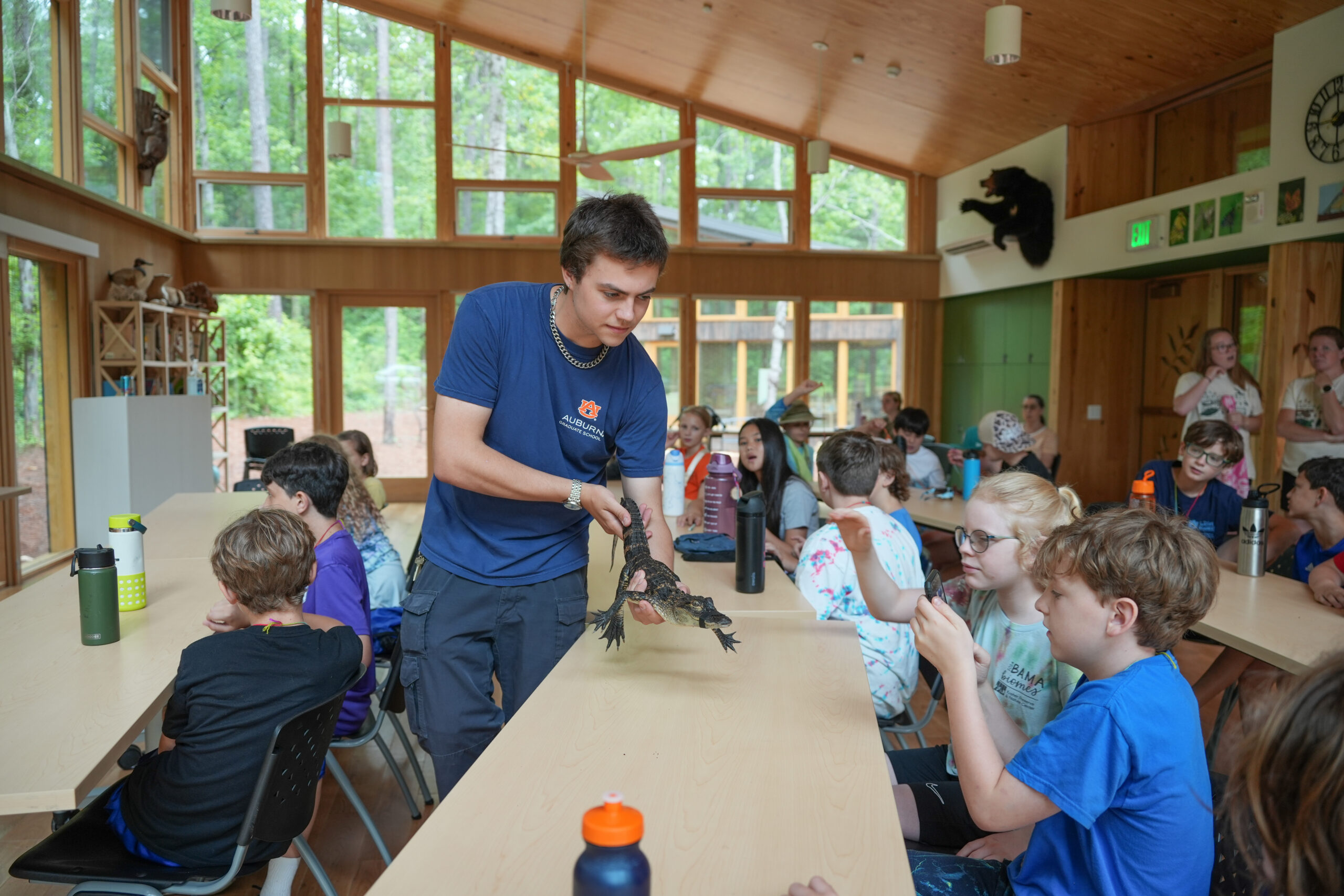 a male CFWE student shows a young boy a juvenile alligator during a class at the KPNC