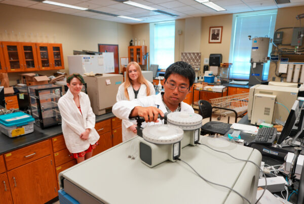 Yang Yang, an assistant professor of forest soils and biogeochemistry in Auburn University’s College of Forestry, Wildlife and Environment, shown with graduate students Marilee Hoyle and Kendall Brents, loads soil samples into an Elemental Analyzer to generate nutrient data for AI-based subsurface biogeochemical modeling.